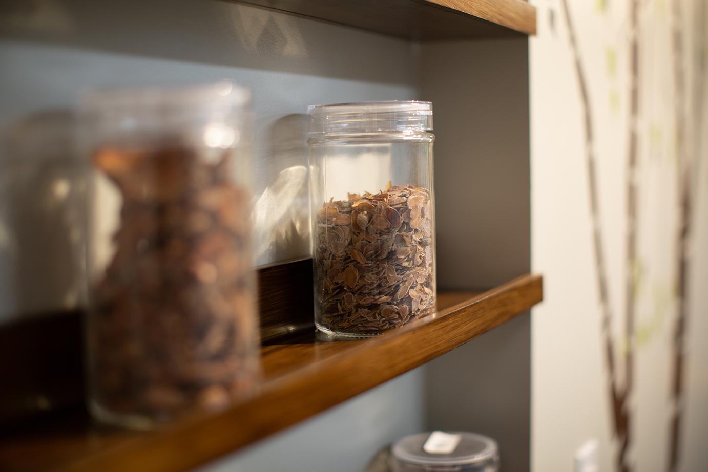 Shelving with jars of herbs utilize a small indent in the wall. Adjacent is a wall tree decal.